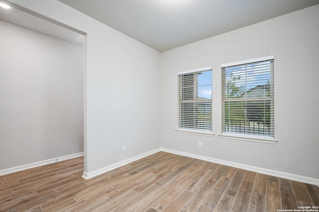 spare room with baseboards and wood finished floors