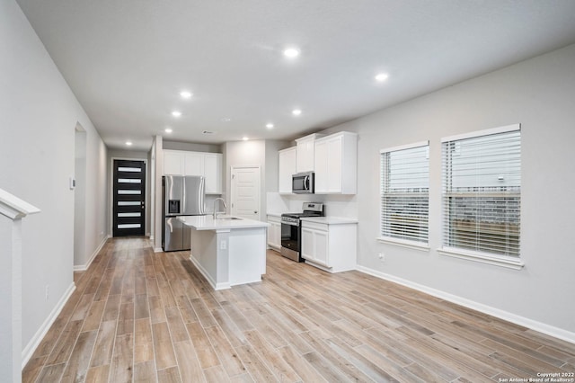 kitchen with stainless steel appliances, light countertops, a sink, and light wood finished floors