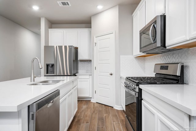 kitchen with visible vents, white cabinets, wood finished floors, stainless steel appliances, and a sink