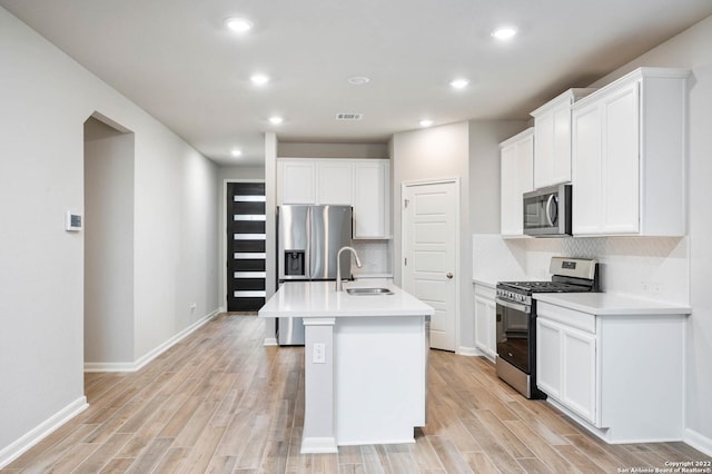 kitchen featuring visible vents, decorative backsplash, appliances with stainless steel finishes, light wood-style floors, and a sink