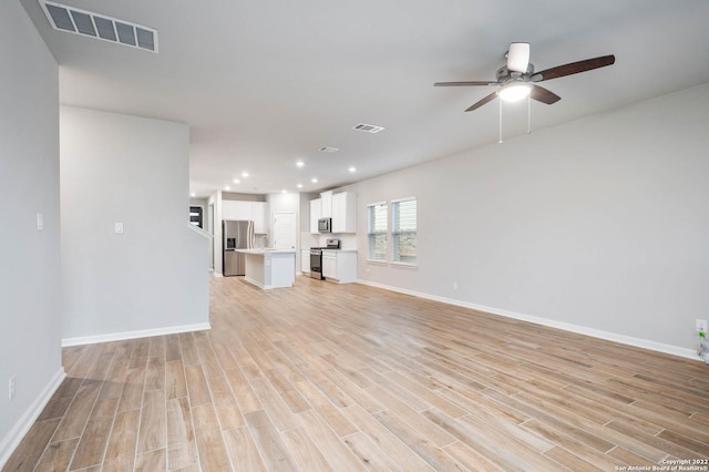 unfurnished living room featuring light wood finished floors, baseboards, and visible vents