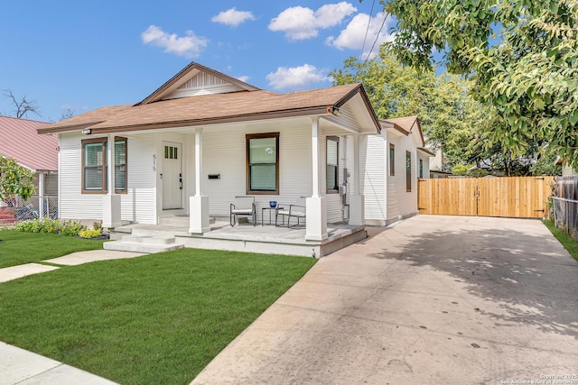 bungalow-style house with a front lawn, a porch, fence, and a gate