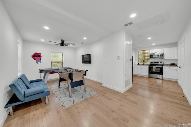 game room featuring light wood finished floors, recessed lighting, visible vents, a sink, and baseboards