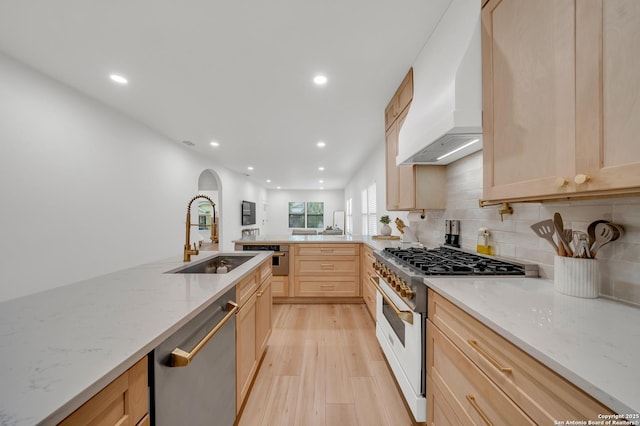 kitchen featuring dishwasher, custom range hood, light brown cabinetry, a sink, and high end white range