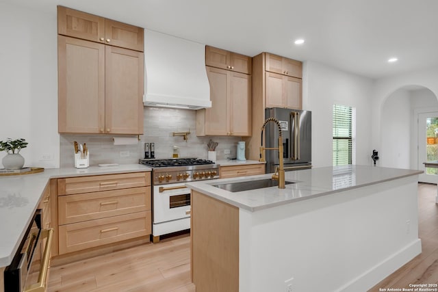 kitchen with light brown cabinetry, gas range, and custom range hood