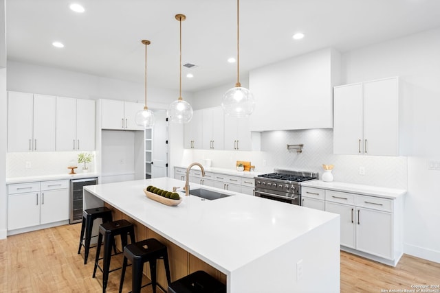 kitchen with beverage cooler, a sink, visible vents, high end stainless steel range oven, and custom exhaust hood