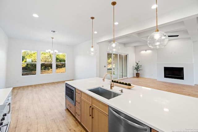 kitchen featuring appliances with stainless steel finishes, open floor plan, light countertops, and a sink