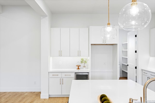 kitchen featuring light countertops, light wood-type flooring, white cabinetry, and decorative backsplash