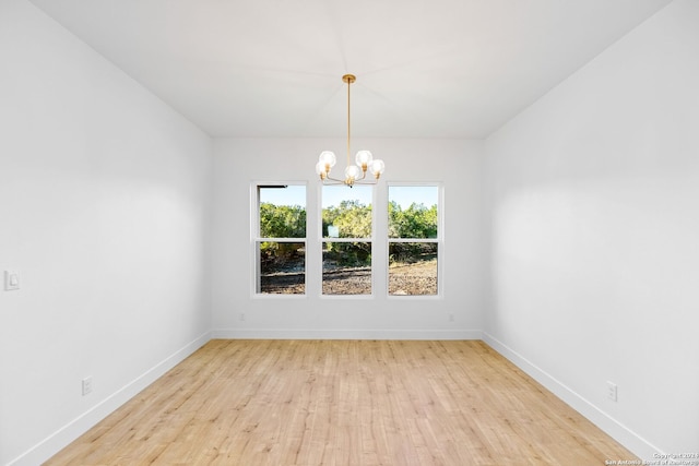 unfurnished dining area with baseboards, light wood-style flooring, and an inviting chandelier