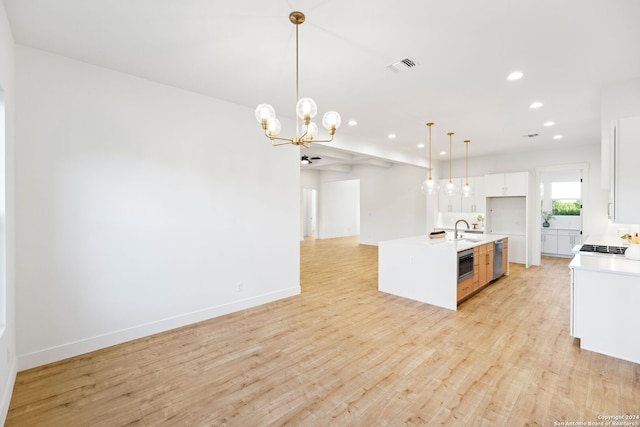 kitchen with light wood finished floors, light countertops, visible vents, white cabinets, and a sink