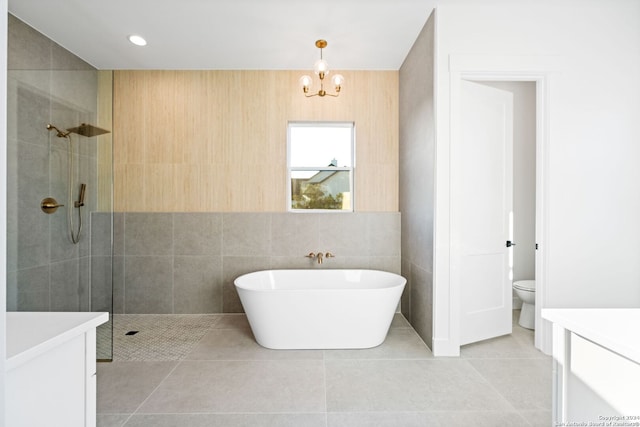 full bathroom featuring toilet, tile patterned floors, a tile shower, a freestanding tub, and tile walls