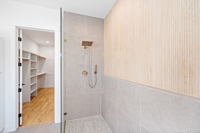 bathroom featuring a spacious closet, tile patterned flooring, and a tile shower