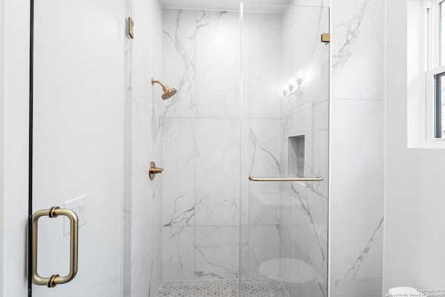 bathroom featuring toilet and a marble finish shower