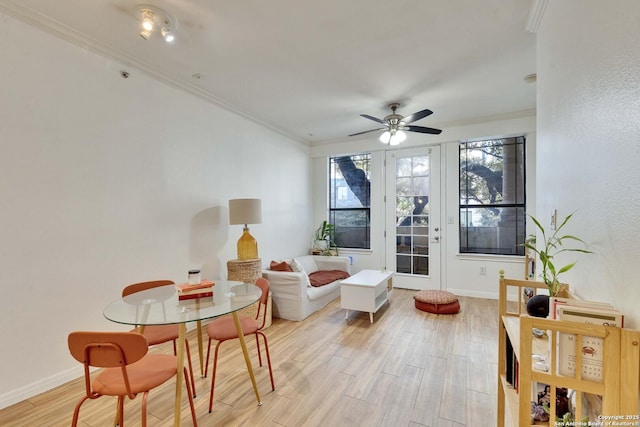 living area featuring baseboards, crown molding, light wood finished floors, and ceiling fan