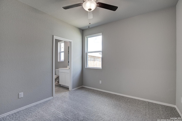 unfurnished bedroom with light carpet, a textured wall, ensuite bath, and baseboards