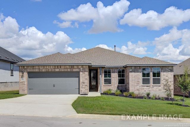 prairie-style house featuring an attached garage, brick siding, a shingled roof, concrete driveway, and a front lawn