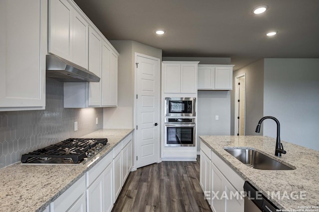 kitchen featuring under cabinet range hood, a sink, white cabinetry, appliances with stainless steel finishes, and dark wood-style floors