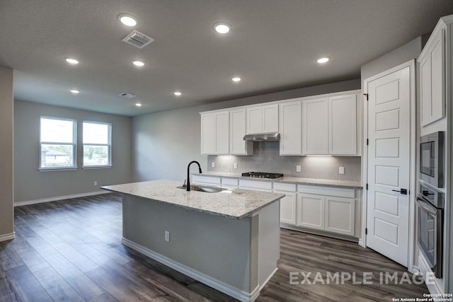 kitchen featuring a kitchen island with sink, dark wood-style flooring, a sink, white cabinets, and backsplash