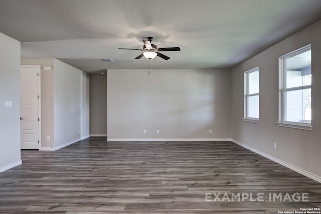 spare room featuring dark wood-type flooring, visible vents, a textured ceiling, and baseboards