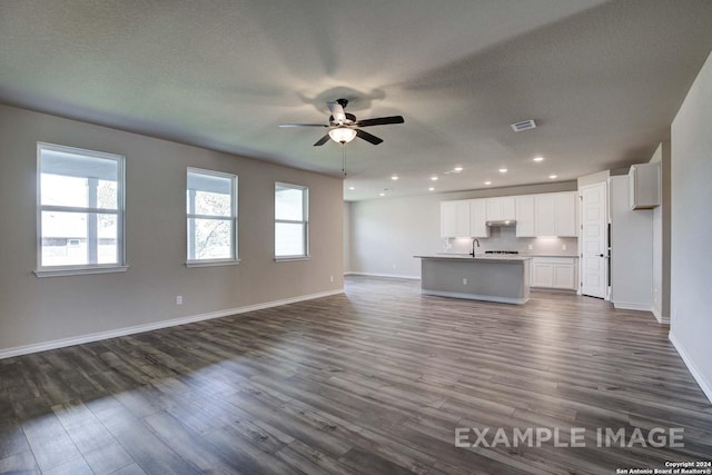 unfurnished living room featuring a ceiling fan, dark wood-style flooring, a sink, and baseboards