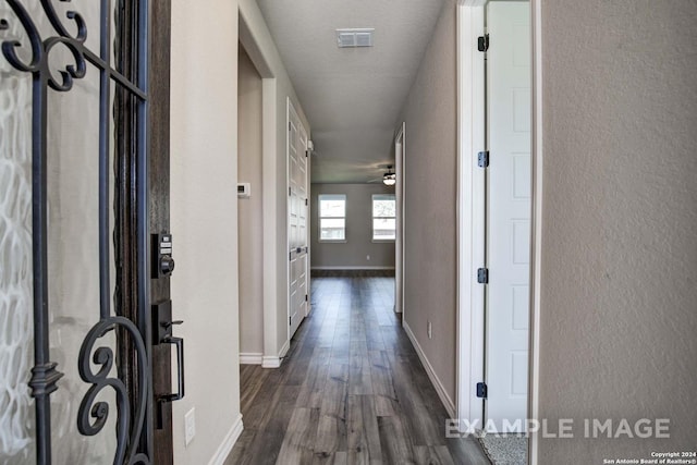 hallway with dark wood-style floors, visible vents, and baseboards