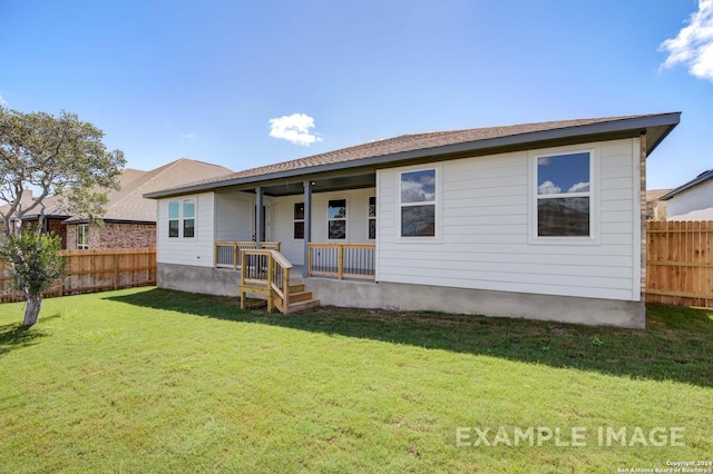 rear view of house with fence and a lawn