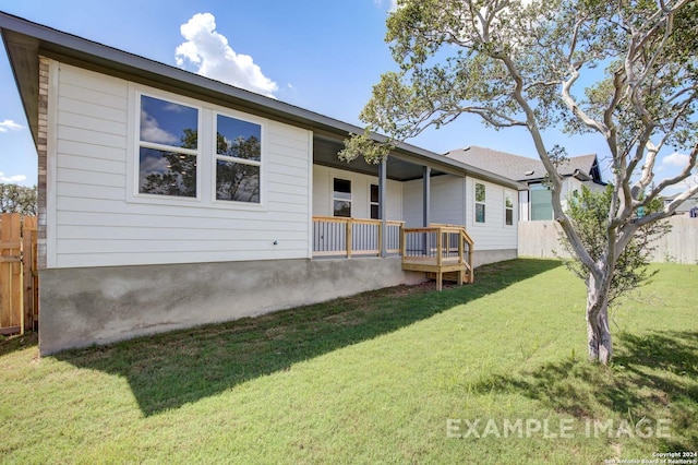 back of property with a porch, a lawn, and fence