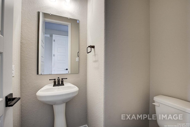 bathroom with a textured wall and toilet