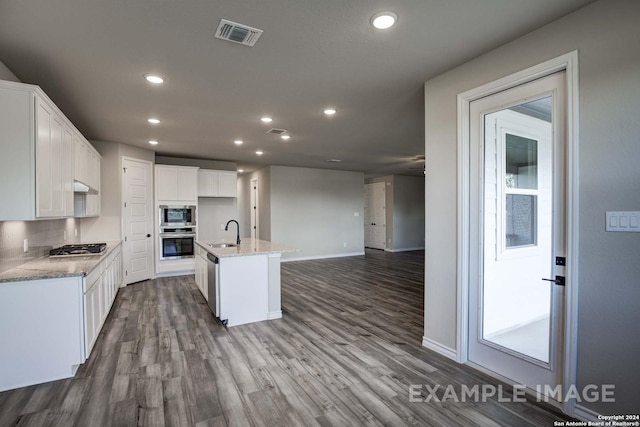 kitchen with visible vents, white cabinets, appliances with stainless steel finishes, wood finished floors, and a sink