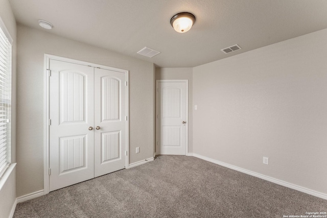 unfurnished bedroom featuring carpet floors, baseboards, visible vents, and a closet