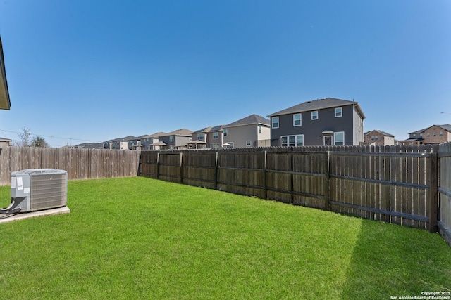 view of yard with central air condition unit, a fenced backyard, and a residential view