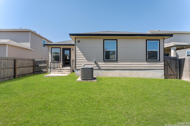 back of property with central AC, a lawn, and a fenced backyard