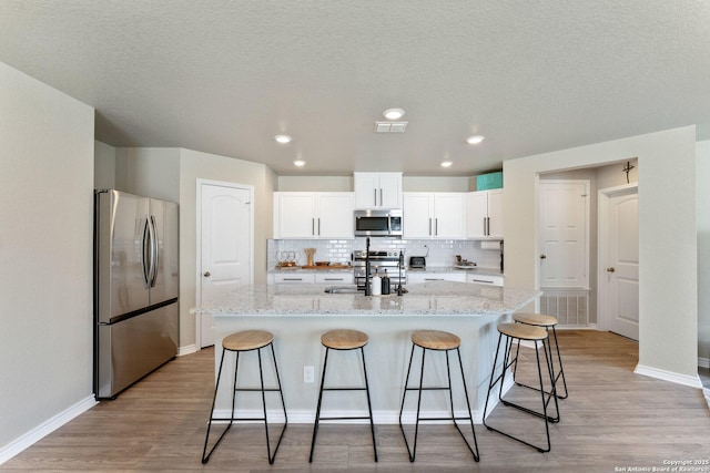 kitchen featuring appliances with stainless steel finishes, a kitchen bar, a sink, and light wood-style floors