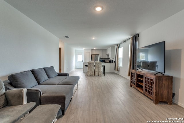 living area with baseboards, recessed lighting, visible vents, and light wood-style floors