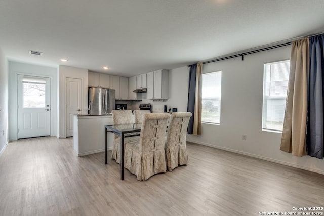 kitchen featuring visible vents, light wood-style flooring, freestanding refrigerator, a kitchen island, and under cabinet range hood