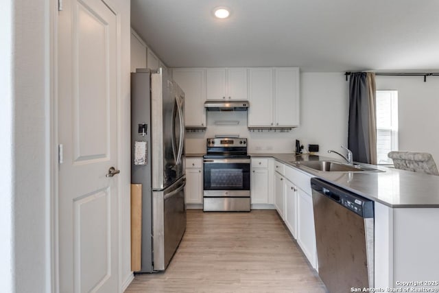 kitchen with light wood finished floors, stainless steel appliances, white cabinetry, a sink, and under cabinet range hood