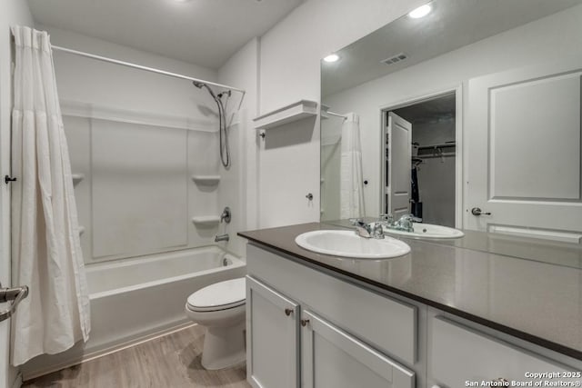 full bathroom featuring toilet, wood finished floors, vanity, visible vents, and shower / tub combo with curtain