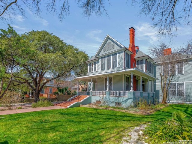 view of front facade featuring a porch, a chimney, and a front yard