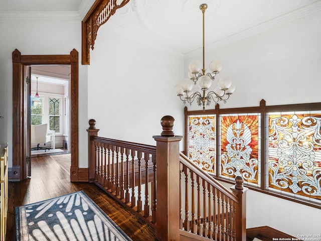 corridor with hardwood / wood-style floors, baseboards, crown molding, a notable chandelier, and an upstairs landing