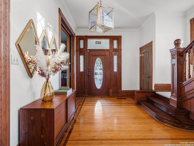 entrance foyer featuring light wood-style floors, stairs, and crown molding