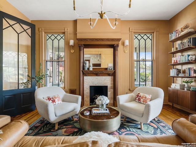 living room featuring wood finished floors, a chandelier, and a premium fireplace