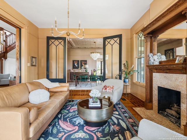 living area featuring a premium fireplace, wood finished floors, baseboards, and a chandelier