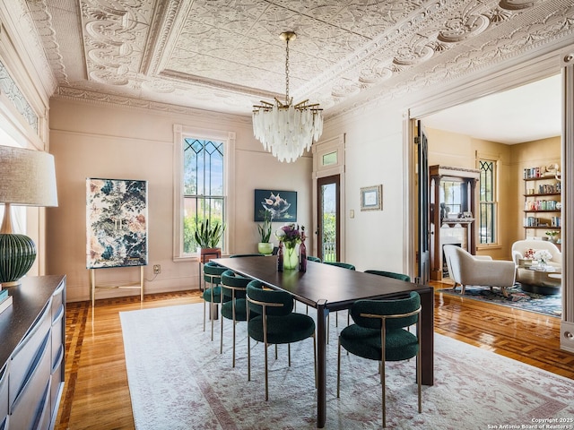 dining room with light wood finished floors, a chandelier, a tray ceiling, ornamental molding, and an ornate ceiling