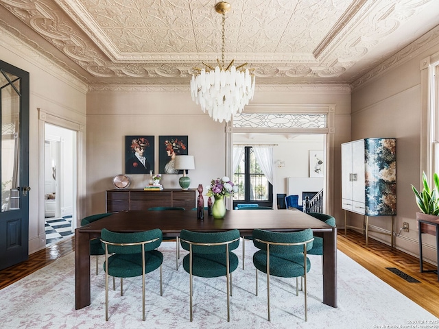 dining room with wood finished floors, visible vents, an ornate ceiling, ornamental molding, and a notable chandelier