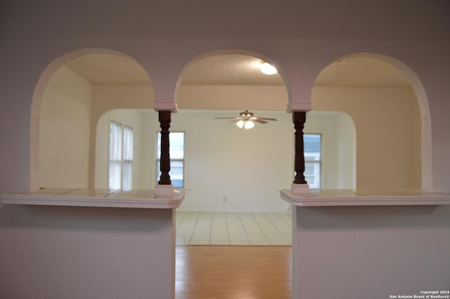 interior space featuring a ceiling fan, a textured ceiling, and wood finished floors