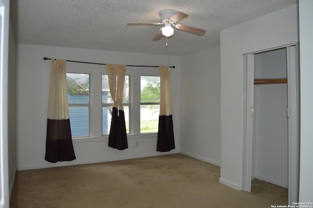 unfurnished bedroom featuring baseboards, a ceiling fan, a textured ceiling, carpet flooring, and a closet