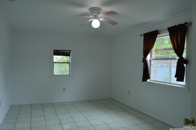 spare room featuring a ceiling fan, a wealth of natural light, baseboards, and light tile patterned floors