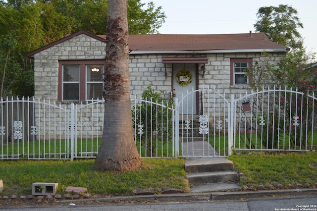 view of front of property with a fenced front yard, stone siding, and a gate