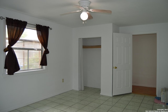 unfurnished bedroom featuring light tile patterned floors, baseboards, a ceiling fan, and a closet