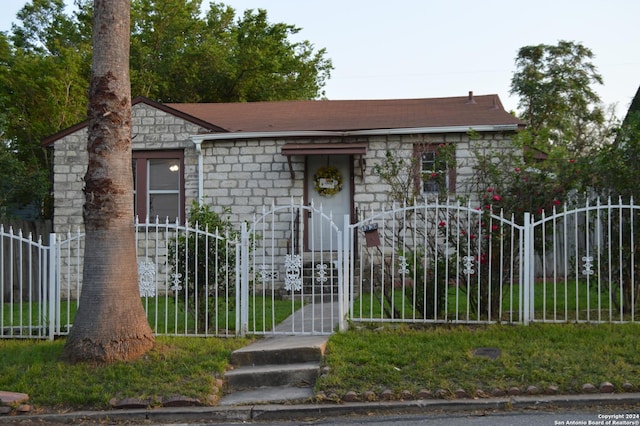view of front facade with stone siding, a fenced front yard, and a gate